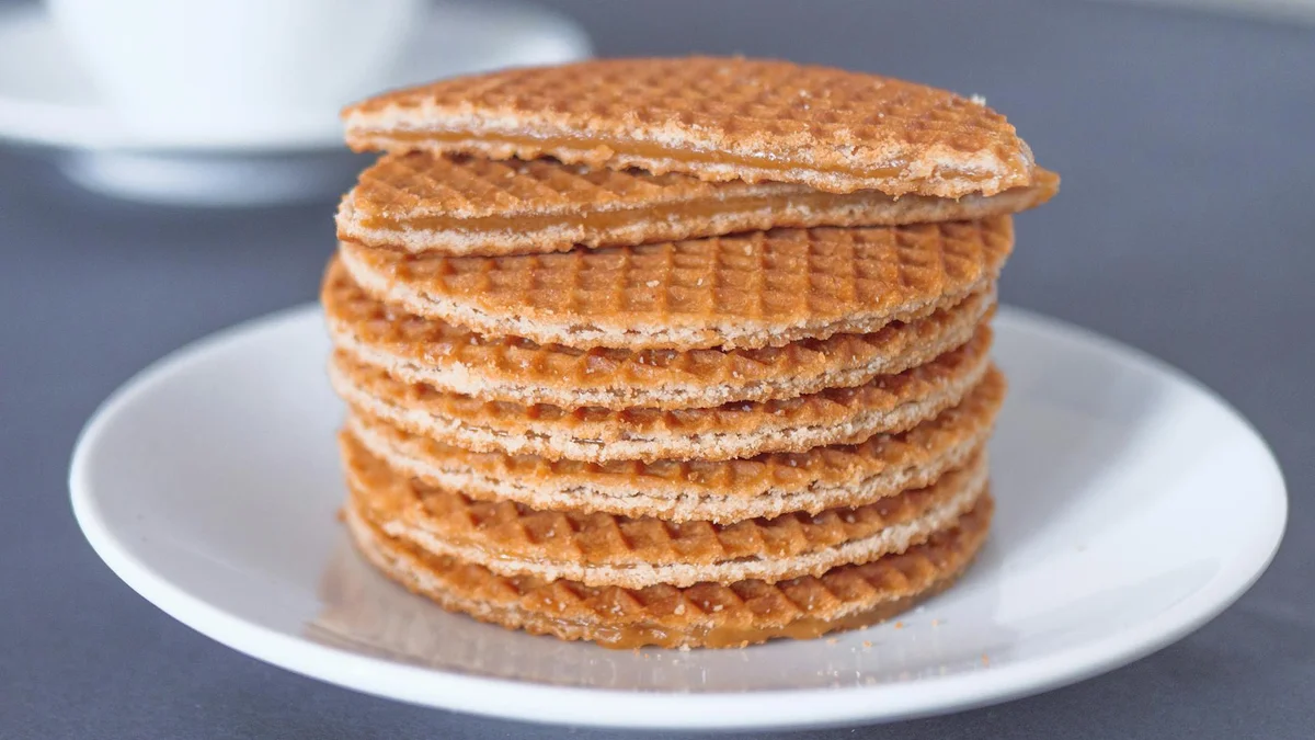 Stroopwafel holandés casero con caramelo entre dos láminas finas de gofre servido junto a un café